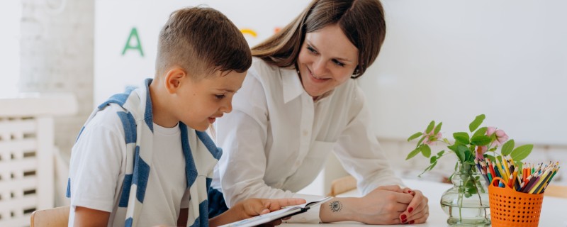 A teaching assistant helps a student with work in the classroom
